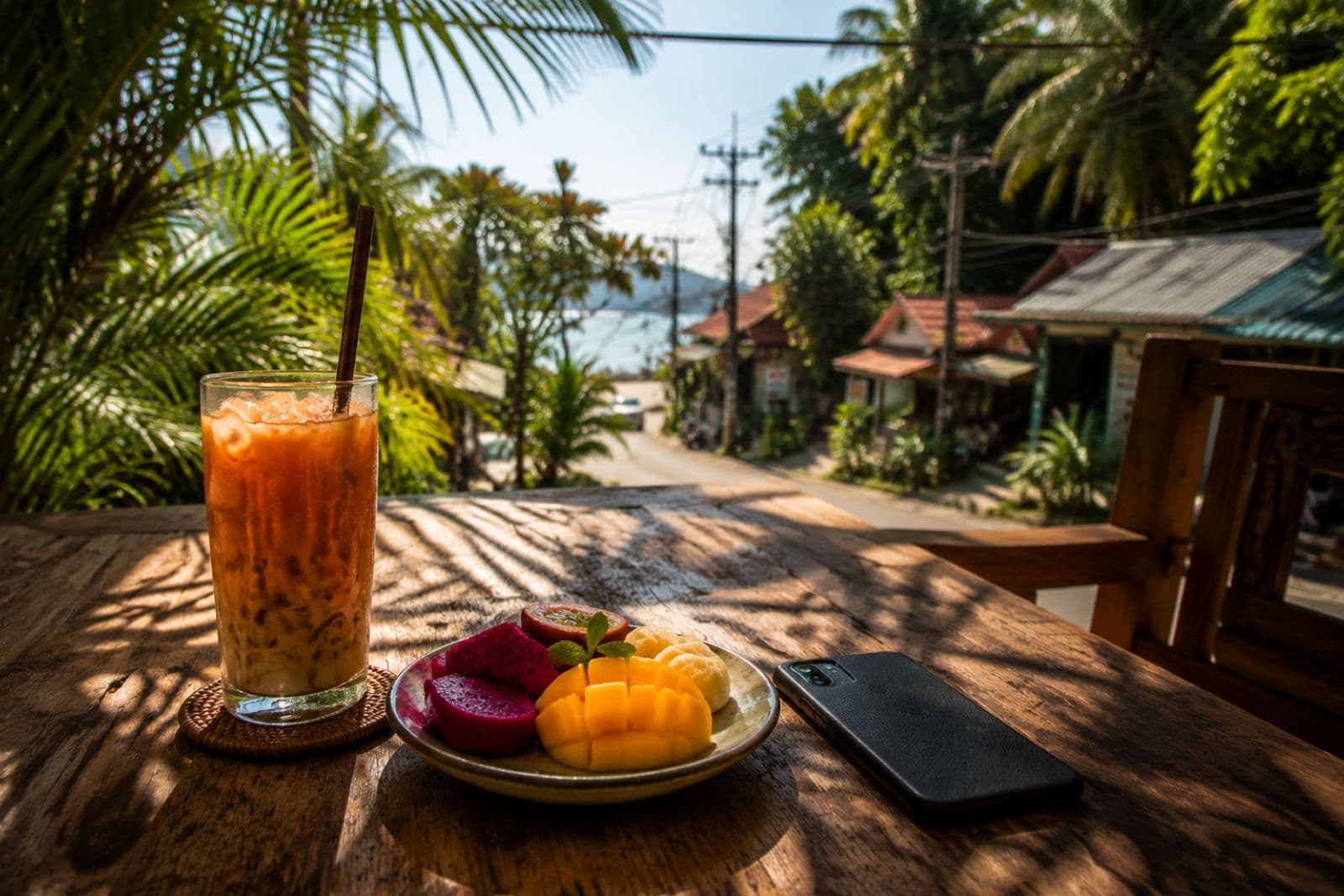 Thai iced tea with tropical fruit plate at a café in morning light