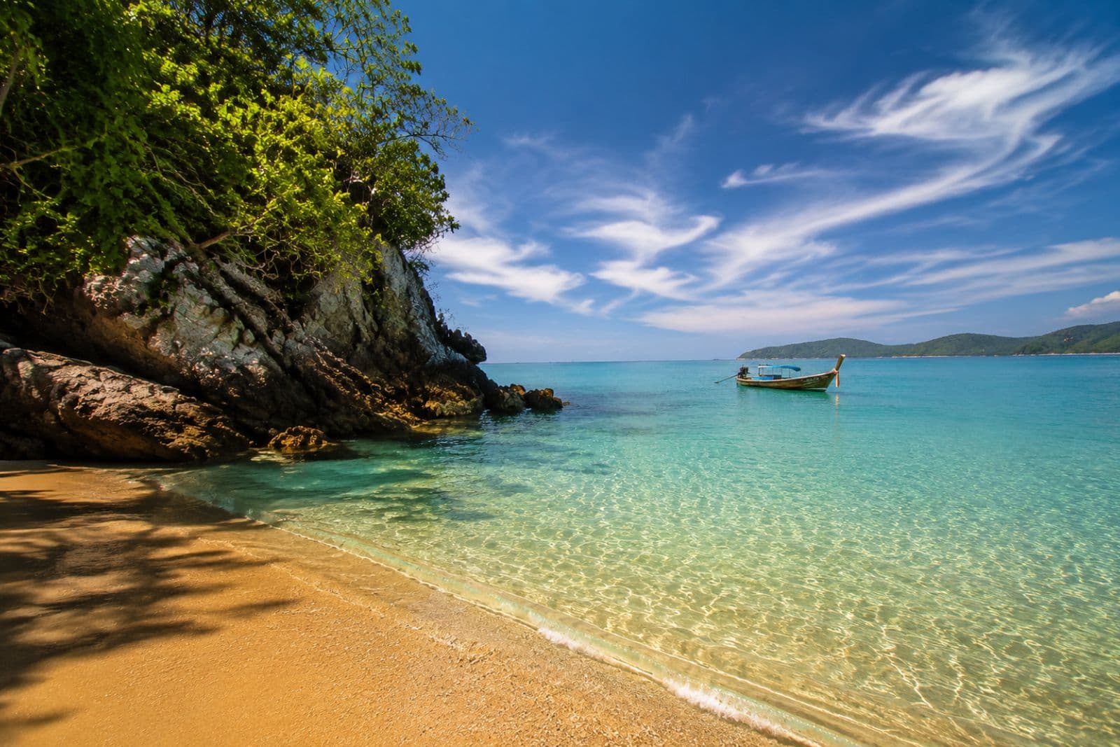 Crystal-clear turquoise water beach with a longtail boat